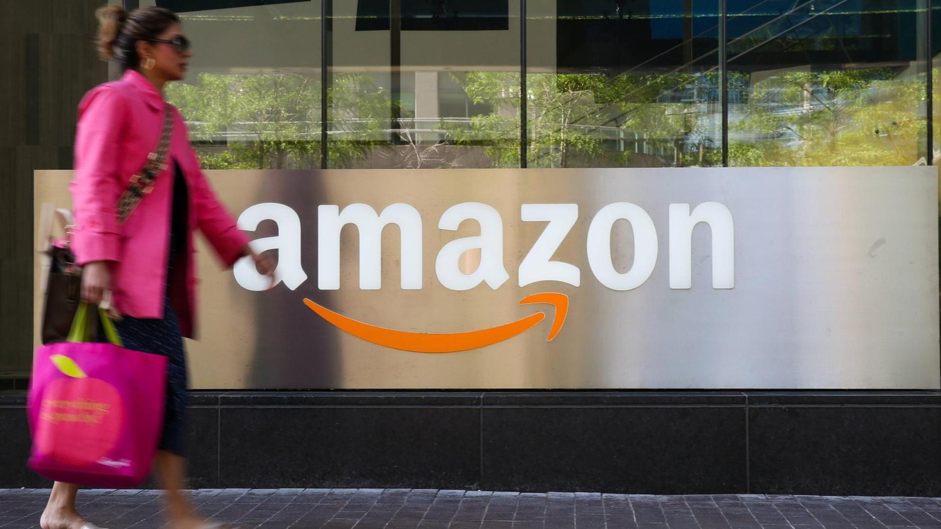 Eine Frau passiert einen Counter mit Amazon Logo in Toronto