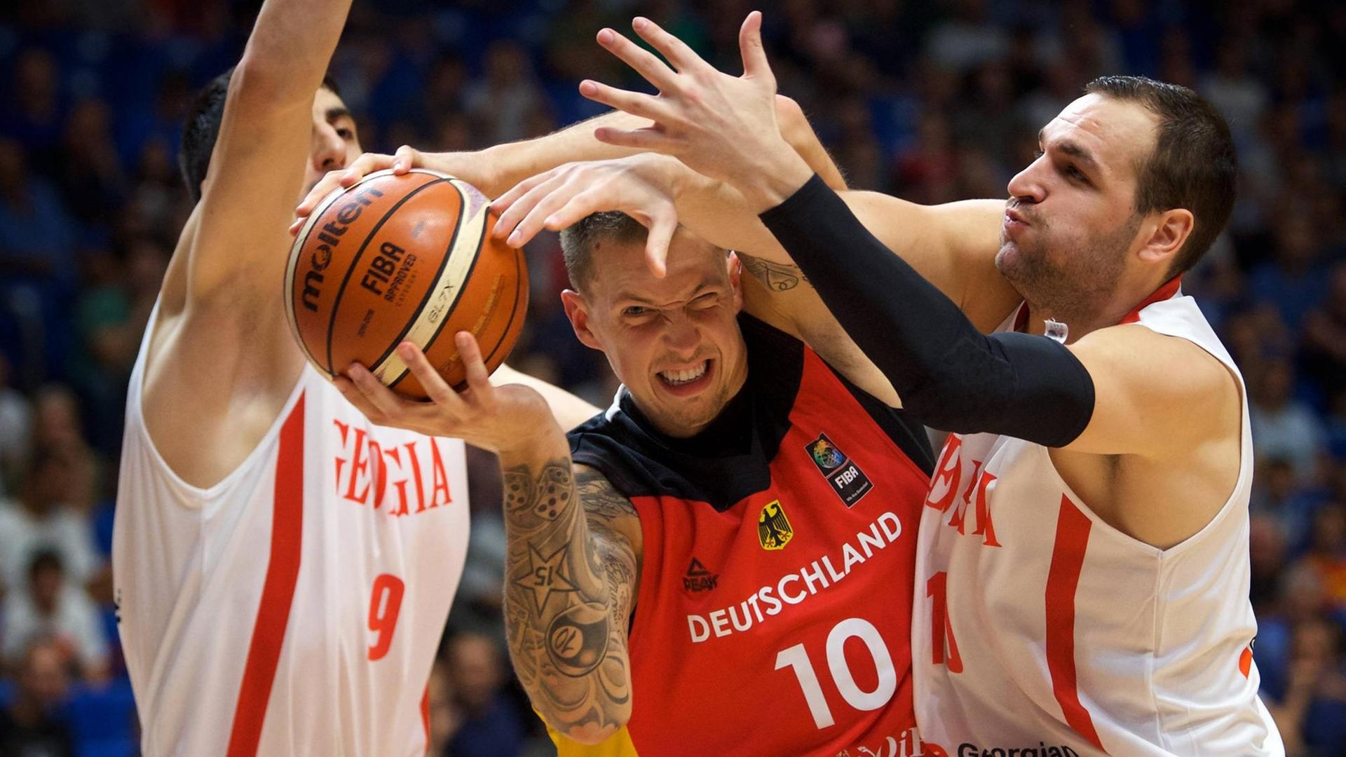 Bei der Basketball-EM in Israel setzt sich Deutschlands Daniel Theis gegen zwei georgische Spieler durch. 