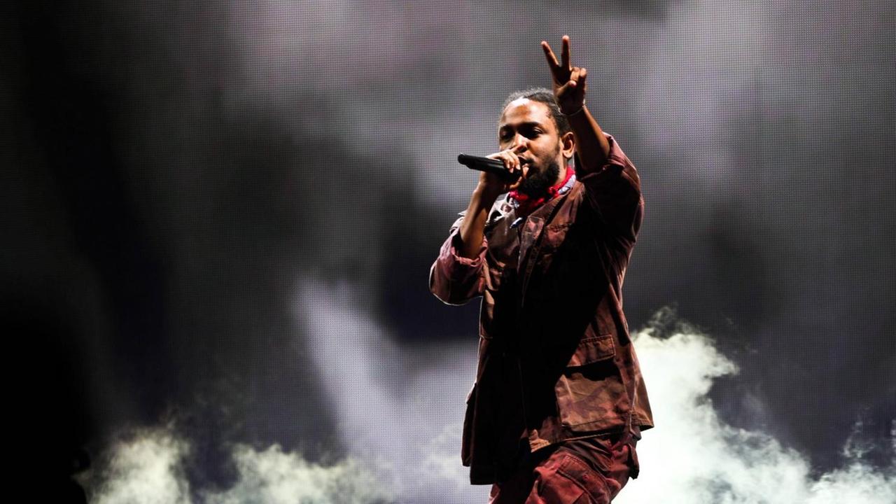 Kendrick Lamar beim Panorama Music Festival 2016 in New York. Der Musiker steht vor dunklem Hintergrund und macht mit einer Hand das Peace-Zeichen