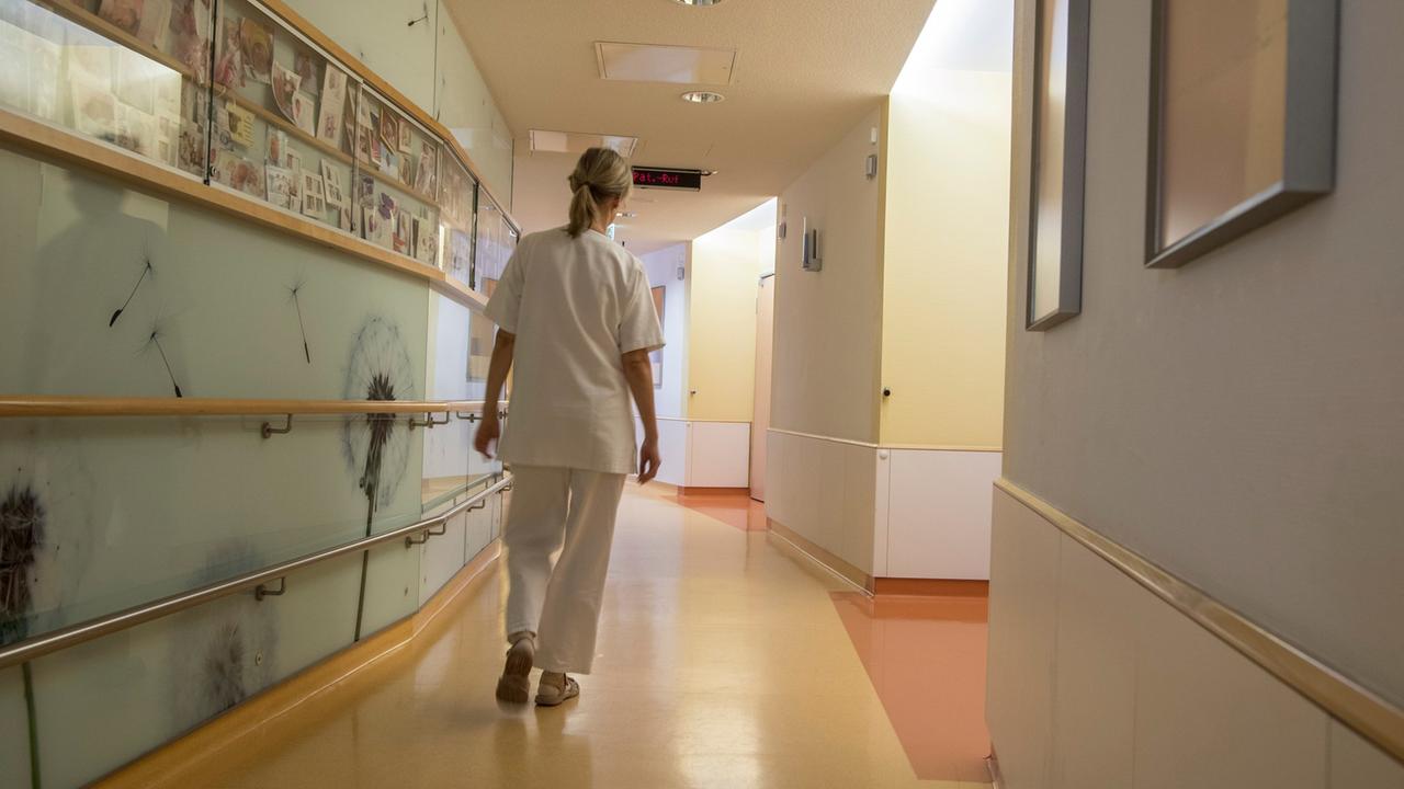 Eine Krankenschwester geht über den ansonsten leeren Flur einer Neugeborenen-Station. 