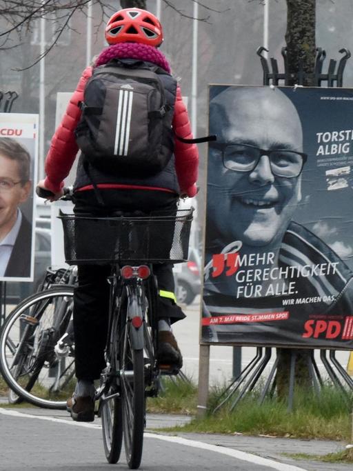 Ein Radfahrer fährt in Kiel an Wahlplakaten mit den Spitzenkandidaten der Landtagswahl, Daniel Günther (CDU) und Torsten Albig (SPD), vorbei