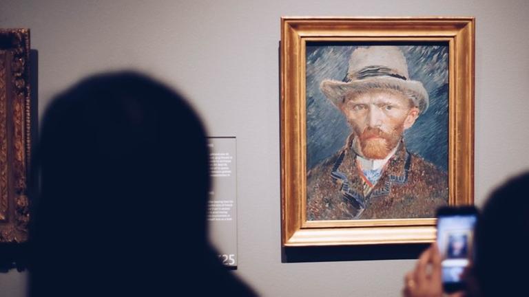 Ein Mann im Rijksmuseum in Amsterdam macht mit seinem Handy ein Foto von van Goghs Selbstporträt.