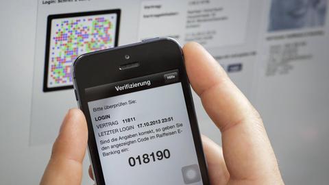 Eine Frau hält ein Handy und ihre Bankkarte in der Hand