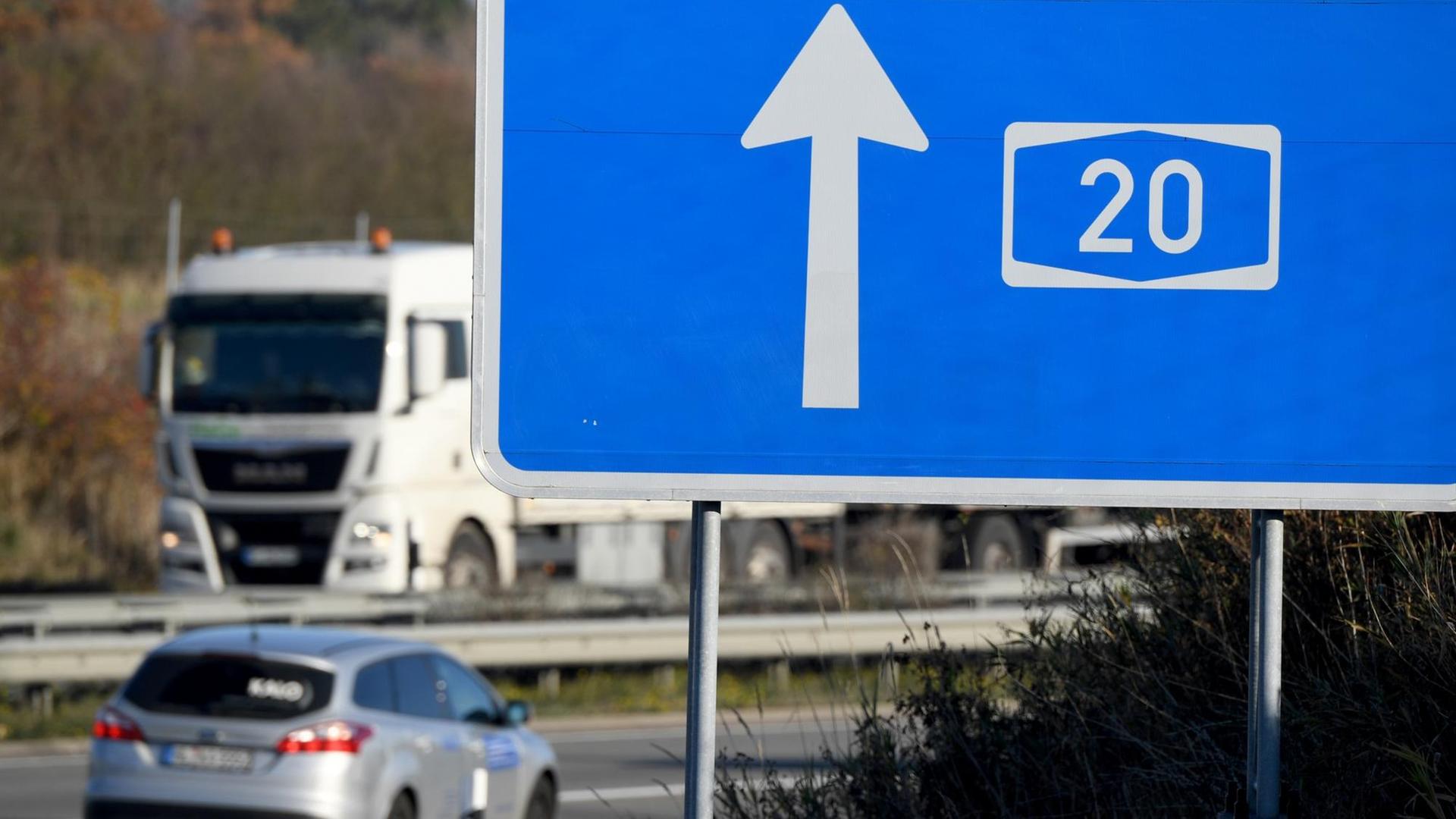 Autos fahren hinter einem Hinweisschild zur A20 auf der Autobahn. Autos fahren hinter einem Hinweisschild zur A20 auf der Autobahn.
