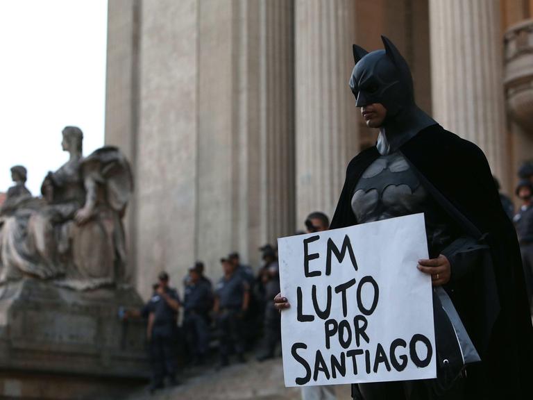 Ein Demonstrant im Batman-Kostüm in Rio de Janeiro während einer Protestaktion gegen die gestiegenen Preise im öffentlichen Nahverkehr in Brasilien. Auf dem Plakat steht: "Trauer um Santiago" – der Kameramann Santiago Andrade war kurz zuvor auf einer Demonstration ums Leben gekommen.