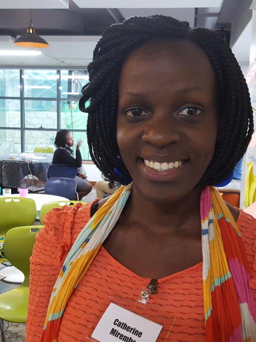 26-Jährige Firmengründerin Catherine Mirembe in Nairobis iHub. Sie lehnt an der Wand. Dahinter grüne Design-Stühle.