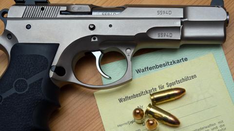 Eine Kaliber-9-mm-Pistole, Patronen und ein Magazin liegen auf einer Waffenbesitzkarte.
