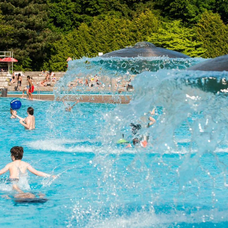Kinder spielen am 20.05.2014 im Freibad Prinzenbad in Berlin unter pilzförmigen Brunnen.