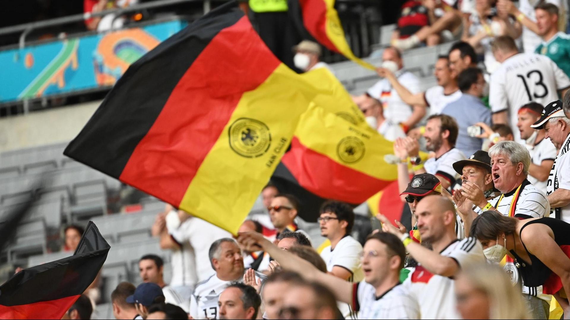 Fußball: EM, Frankreich - Deutschland, Vorrunde, Gruppe F, 1. Spieltag in der EM-Arena München. Fans feiern auf der Tribüne mit deutsche Fahnen vor dem Spiel. Important: For editorial news reporting purposes only. Not used for commercial or marketing purposes without prior written approval of UEFA. Images must appear as still images and must not emulate match action video footage. Photographs published in online publications (whether via the Internet or otherwise) shall have an interval of at least 20 seconds between the posting.
