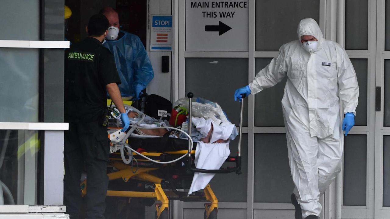 Liverpool: Ein Krankenhausmitarbeiter in Schutzausrüstung zieht ein Bett hinter sich her.