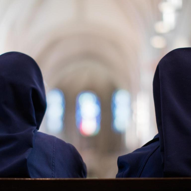 Zwei Ordensschwestern sitzen im Dom. 
