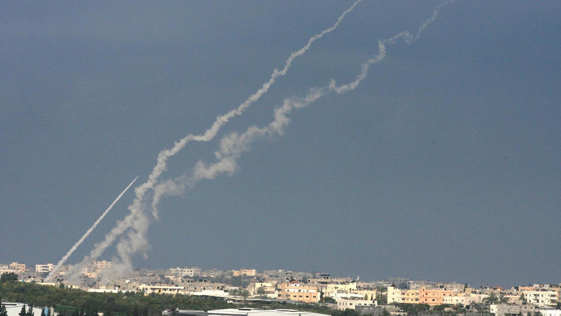 Von Gaza-Stadt aus steigen Rauchschweife der Raketen hoch; das Bild ist aus weiter Entfernung aufgenommen.