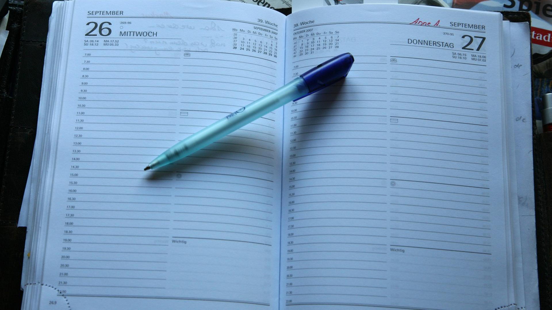 Voller Schreibtisch mit Terminkalender.