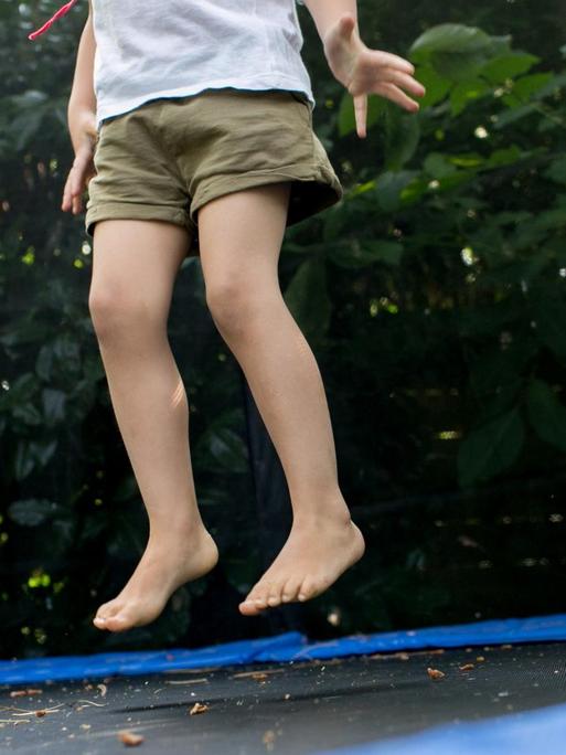 Ein Mädchen springt am 14.07.2018 in einem Garten in Düsseldorf (Nordrhein-Westfalen) auf einem Trampolin.