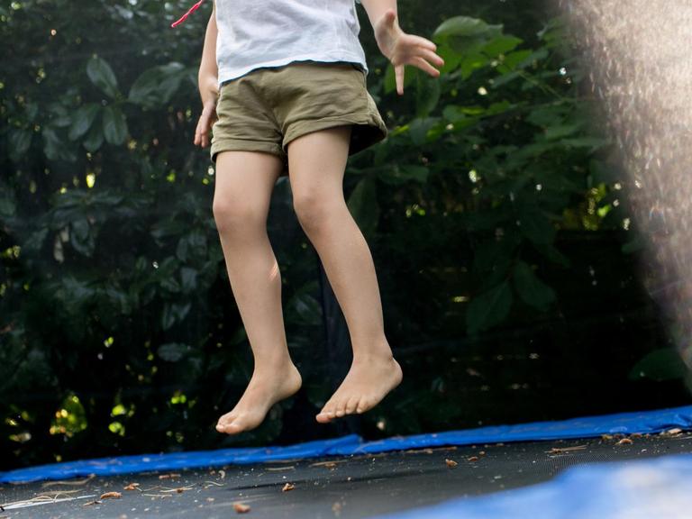 Ein Mädchen springt am 14.07.2018 in einem Garten in Düsseldorf (Nordrhein-Westfalen) auf einem Trampolin.