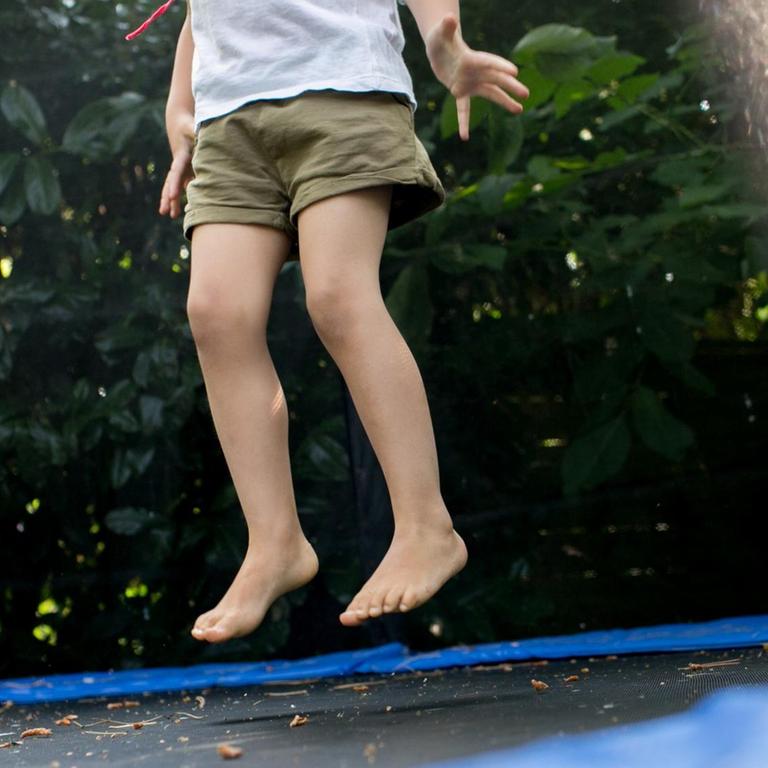 Ein Mädchen springt am 14.07.2018 in einem Garten in Düsseldorf (Nordrhein-Westfalen) auf einem Trampolin.