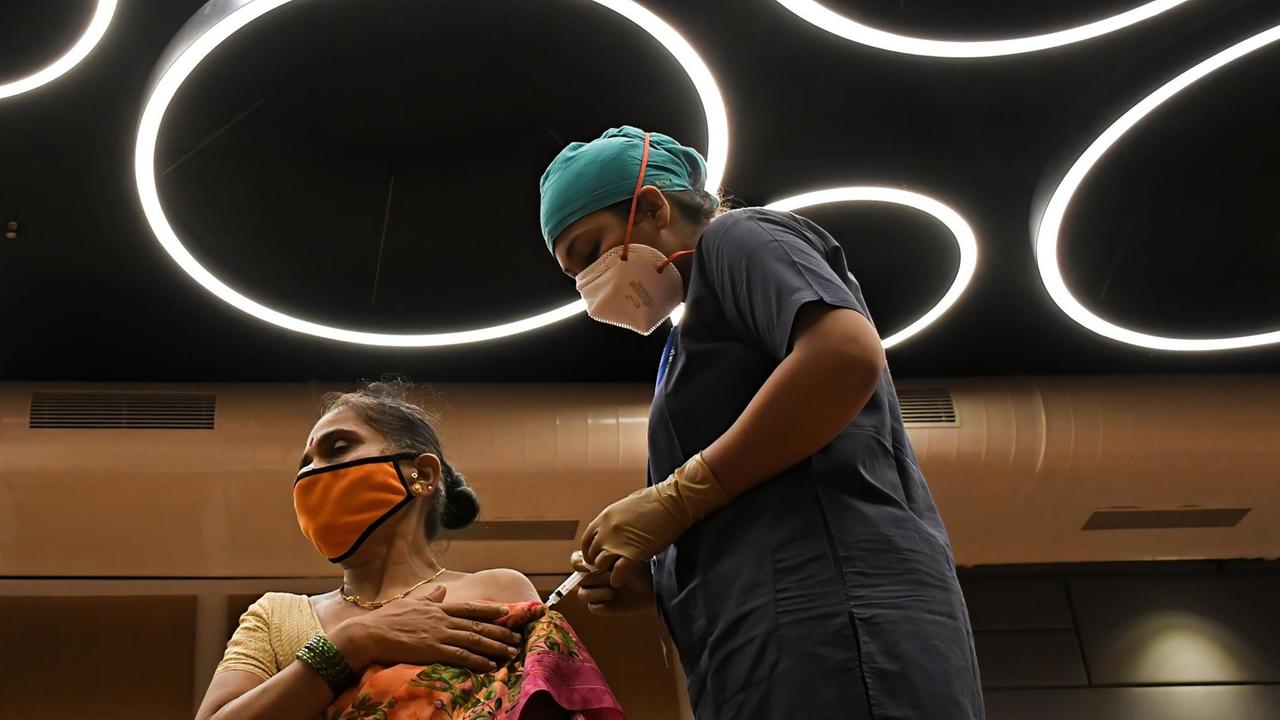 Eine Gesundheitsmitarbeiterin impft eine Frau in Mumbai, Indien. 