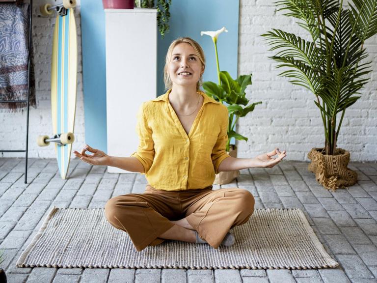 Junge Frau versucht in ihrer Wohnung zu meditieren.
