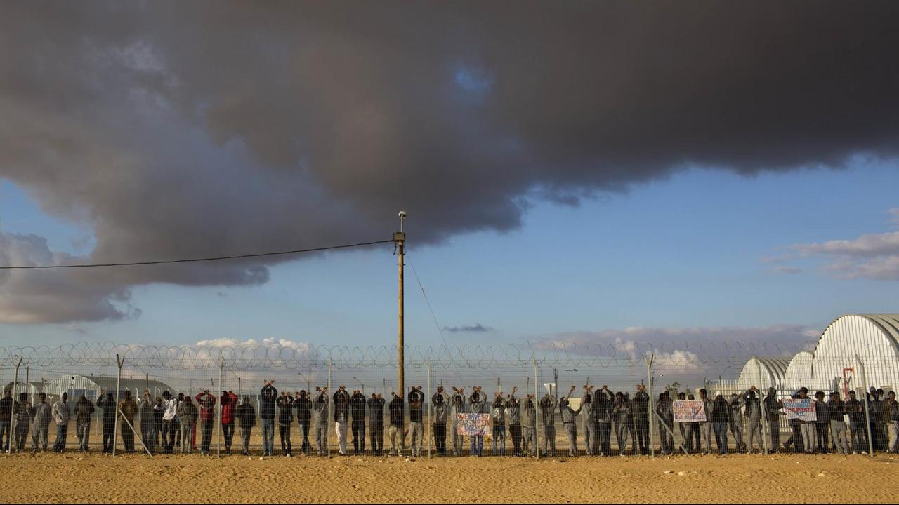 Afrikanische Migranten stehen am Zaun des Internierungslagers in Holot in der Negev-Wüste im Süden Israels.