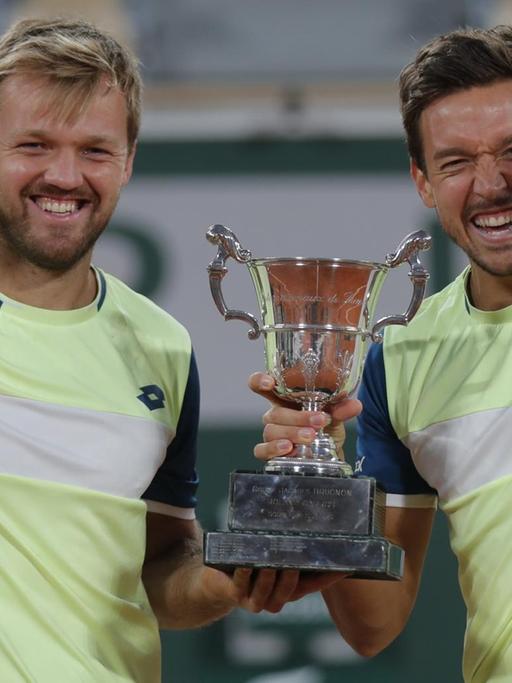 Kevin Krawietz (l) und Andreas Mies aus Deutschland feiern mit der Trophäe den Finalsieg im Doppel der French Open.