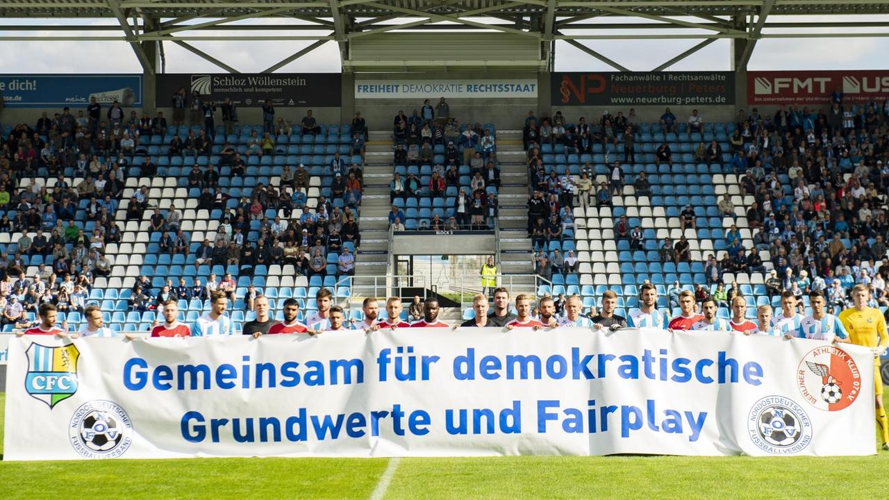 Spieler des Chemnitzer FC und des Berliner AK halten vor Beginn des Spiels ein Banner mit der Aufschrift "Gemeinsam für demokratische Grundwerte und Fairplay".
