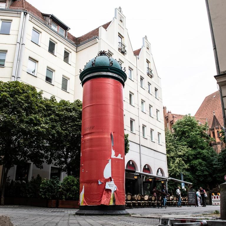 Eine rot abgeklebte Litfaßsäule im Berliner Nikolaiviertel. 