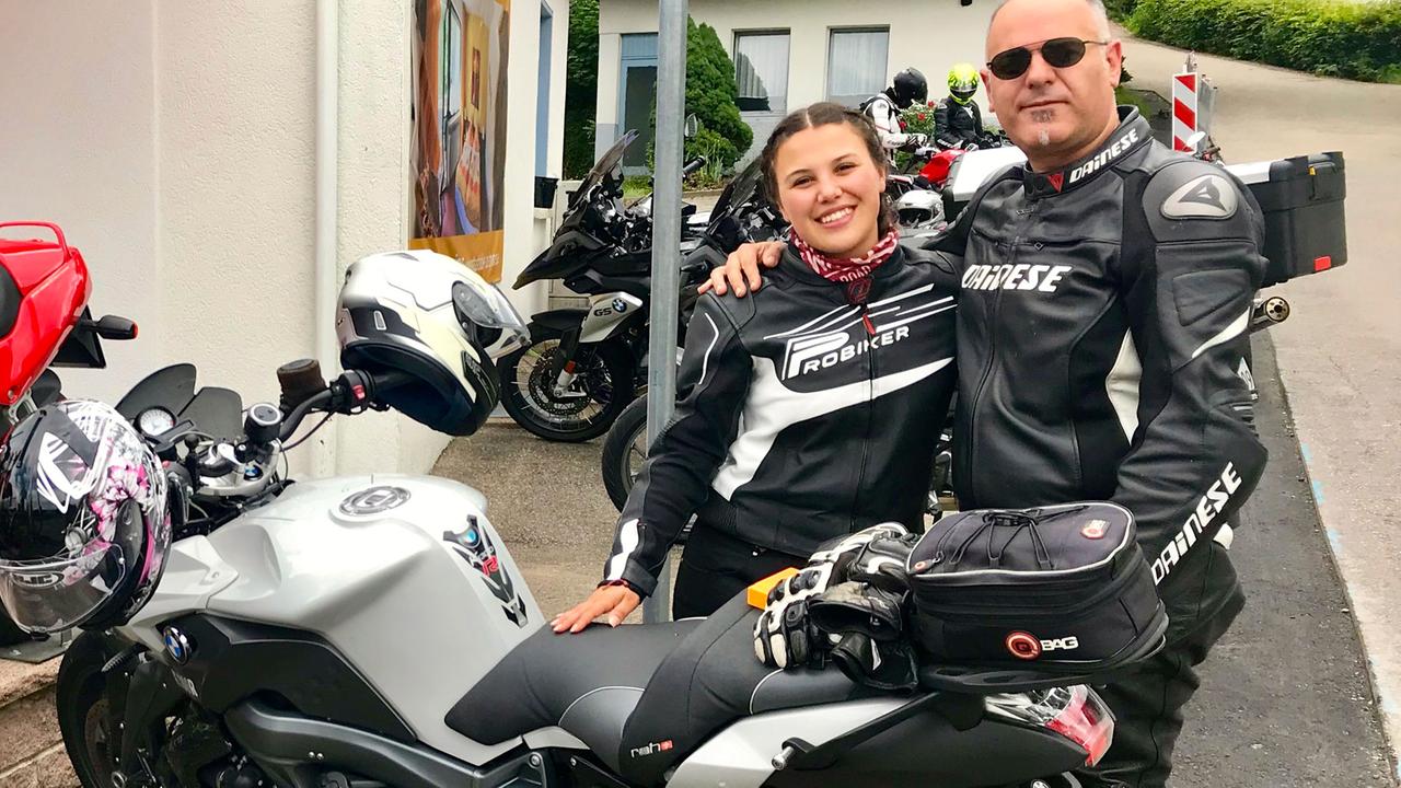 Der Schweizer Motorradfahrer Francisco mit seiner Begleiterin stehen hinter ihrem Motorrad.