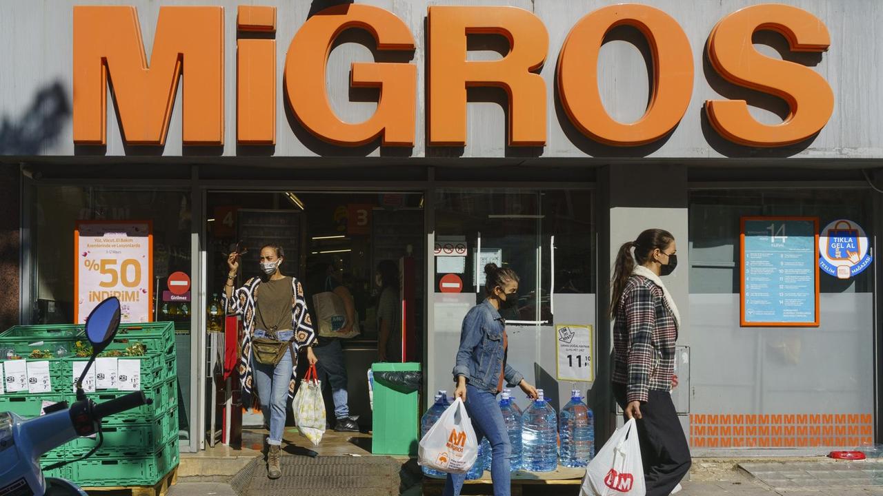 Drei Frauen mit vollen Tüten kommen aus dem Supermarkt Migros in Istanbul.
