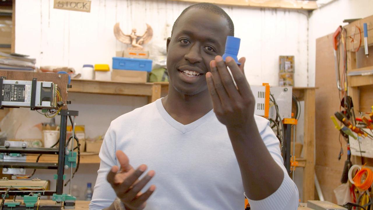 Roy Ombatti von AB3D aus Kenia zeigt ein Ersatzteil, das er mit seinem selbstgebauten 3D-Drucker hergestellt hat
