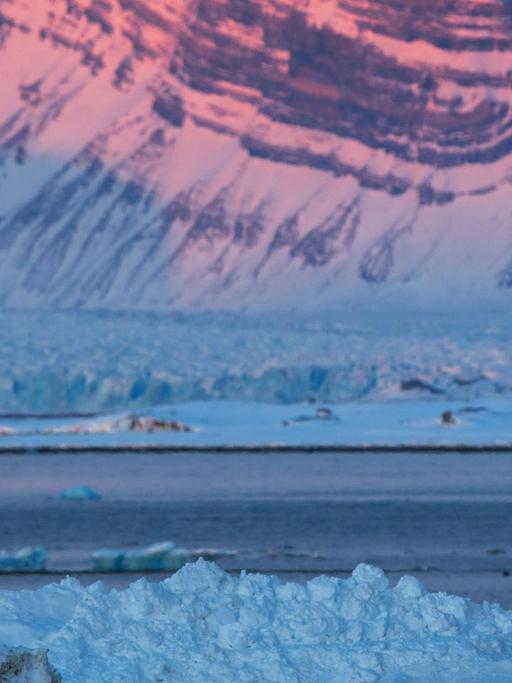 Besucher fotografieren am 09.04.2015 die von der untergehenden Sonne angeleuchteten Spitzen der "Tre Kroner" am Kongsfjord-Gletscher in Ny-Ålesund auf Spitzbergen (Norwegen).