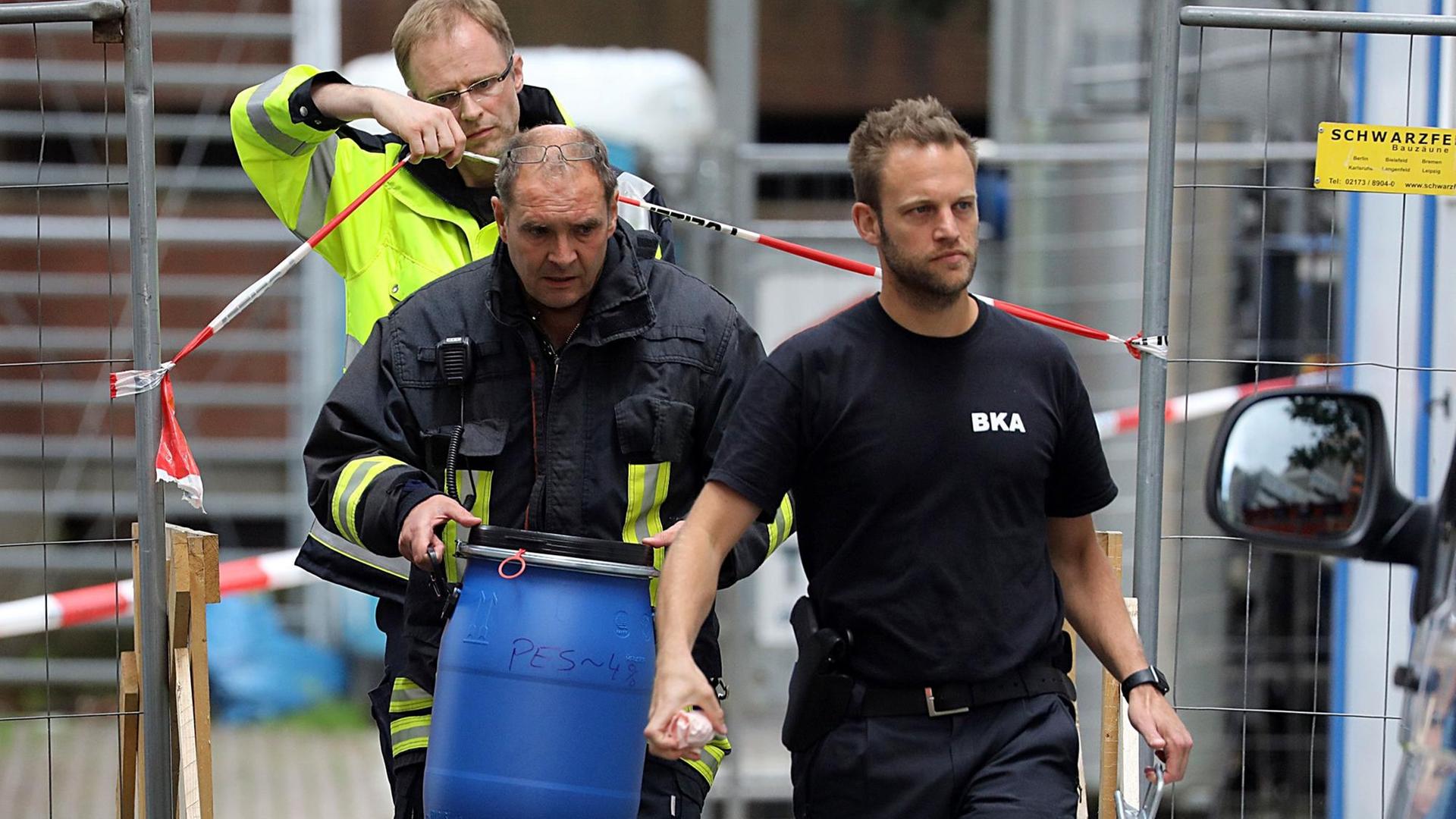 Ein Feuerwehr-Mann trägt in Köln eine blaue Tonne aus einem Haus Ein Feuerwehr-Mann trägt in Köln eine blaue Tonne aus einem Haus