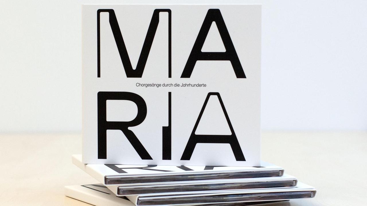 Kleiner Stapel der neuen CD mit dem Titel "Maria", der in großen schwarzen Buchstaben auf weißem Grund zu lesen ist.