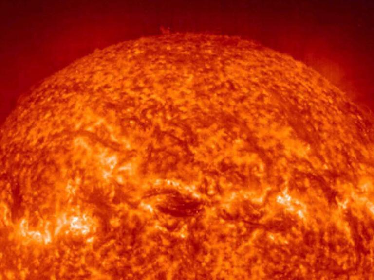 Als glutroter, lebensfeindlicher Feuerball präsentiert sich die 149,6 Millionen Kilometer von der Erde entfernte Sonne aus der Nähe: Das UV-Foto wurde vom EIT-Teleskop an Bord der Sonnen- und Heliosphären-Observationsraumsonde SOHO der NASA am 20.12.2000 aufgenommen. Die Fleckenstruktur ergibt sich durch die unterschiedlichen Temperaturen (zwischen 60000 und 80000 Grad) auf der Sonnenoberfläche. In der Korona, dem leuchtenden, äußersten Kranz um die Sonne, werden Temperaturen bis 1,5 Millionen Grad Celsius erreicht.