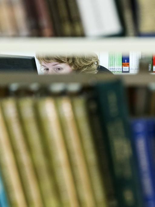 Die Augen einer Frau sind zwischen Bücherregalen in einer Bücherrei in Russland zu sehen
