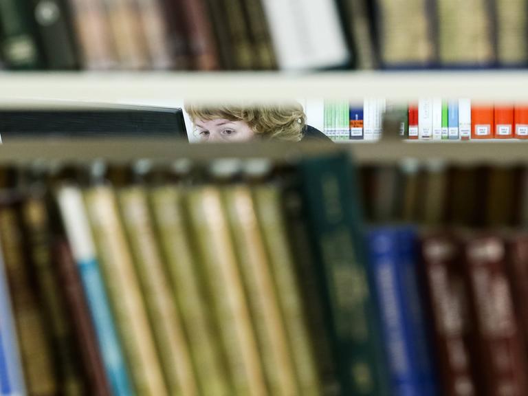 Die Augen einer Frau sind zwischen Bücherregalen in einer Bücherrei in Russland zu sehen