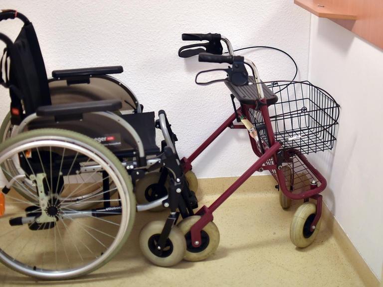 Ein Rollator und ein Rollstuhl stehen in einer Pflegeeinrichtung in einer Ecke.
