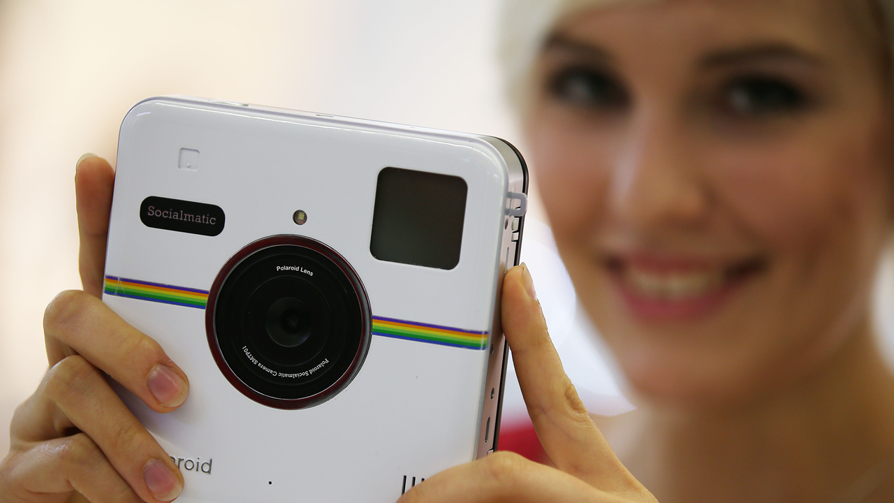 Eine Frau schaut sich auf der Messe Photokina die Polaroid Kamera Socialmanic an (2014). 