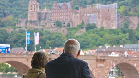 Ein Mann und eine Frau schauen aus der Ferne auf das Heidelberger Schloss.
