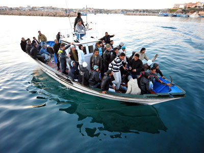 Auf einem kleinen Boot im Meer sind dicht gedrängt Flüchtlinge zu sehen, vor Lampedusa.