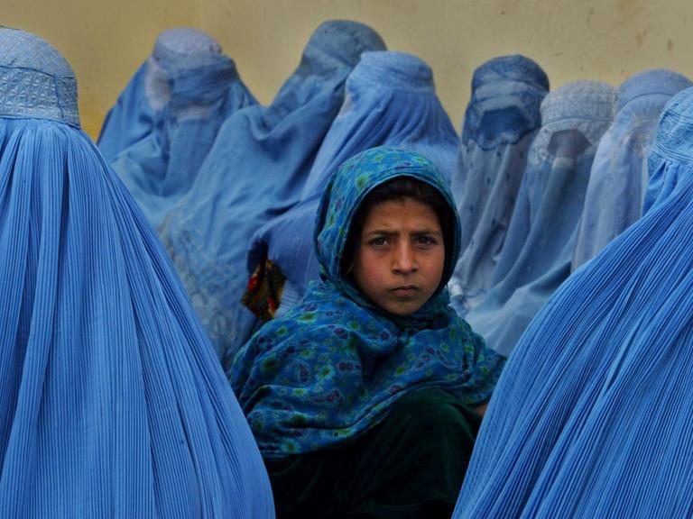 Ein kleines Mädchen umringt von afghanischen Frauen in blauen Burkas warten vor einer Klinik in der afghanischen Stadt Kalakan auf medizinische Hilfe.