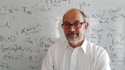 Der Mathematiker Nigel Hitchin steht vor einer beschriebenen Tafel