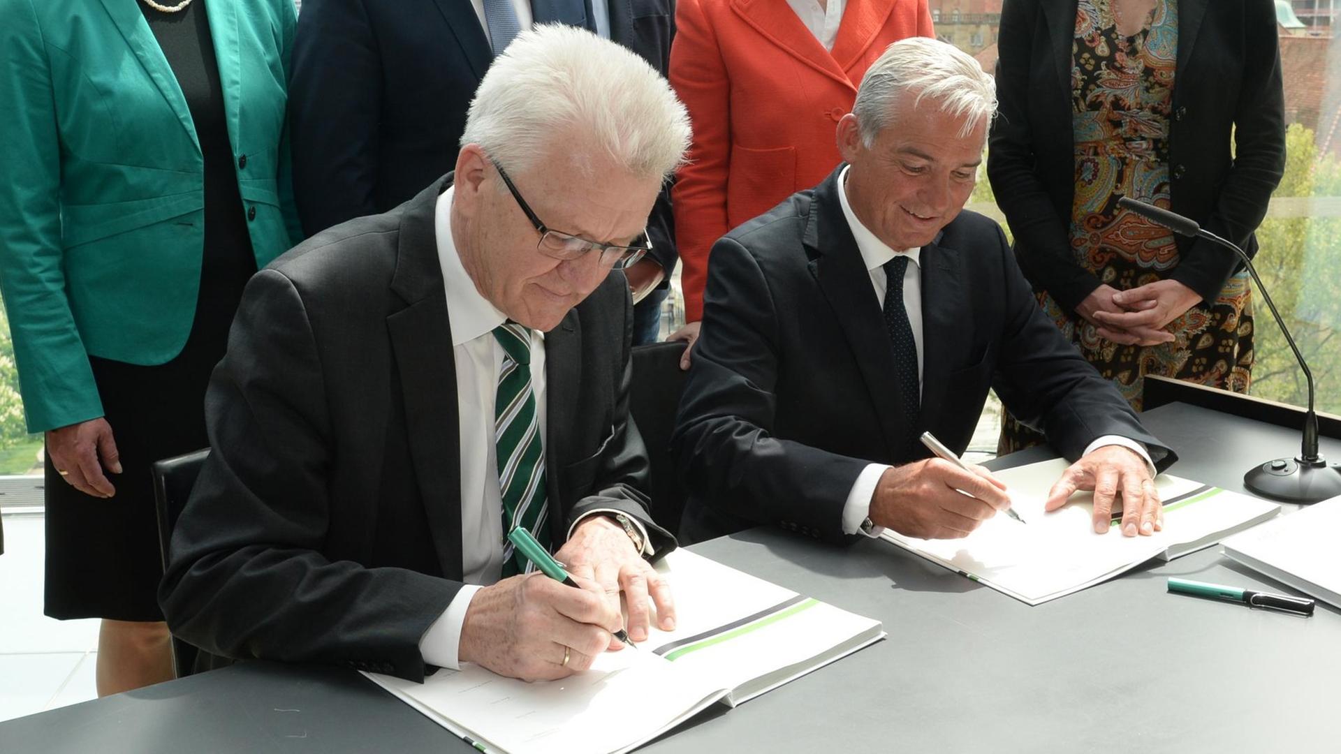 Winfried Kretschmann und der baden-württembergische CDU-Vorsitzende Thomas Strobel (r.) unterschreiben am 09.05.2016 in Stuttgart den Koalitionsvertrag. 