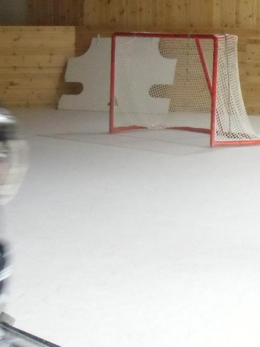 Zwei Kinder trainieren in einer Eishockey Halle auf Polyethylen-Boden mangels Eiszeiten.