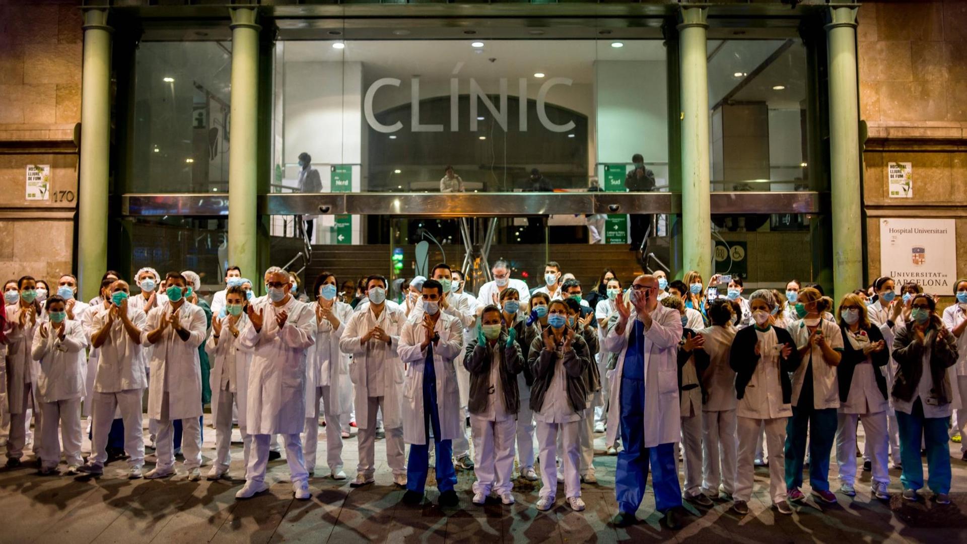 Pflegekräfte stehen am 25. März vor einem Krankenhaus in Barcelona und applaudieren.