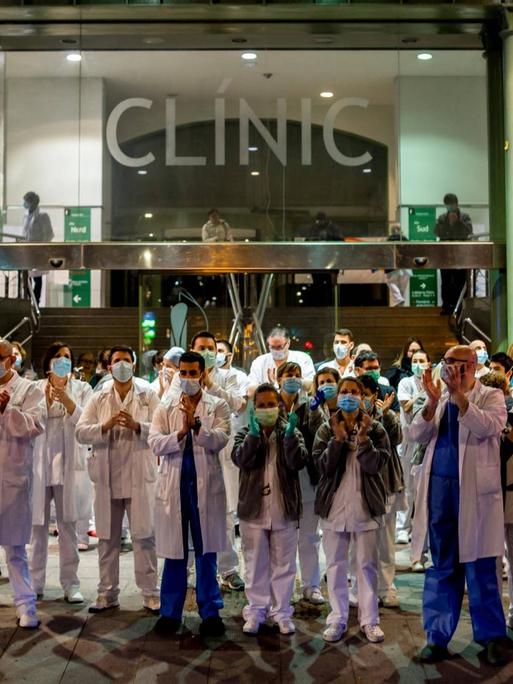 Pflegekräfte stehen am 25. März vor einem Krankenhaus in Barcelona und applaudieren.