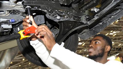 Ein Flüchtling schraubt bei seiner Ausbildung zum KFZ-Mechaniker am Unterboden eines PKW / anlässlich der Internationalen Handwerksmesse 2016 in München