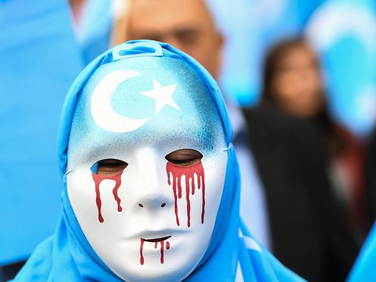27. April 2018 in Brüssel: Maskierte Person auf einem Protestmarsch für die Schließung der chinesischen Umerziehungslager, in denen Uiguren aus der Autonomen Region Xinjiang festgehalten werden