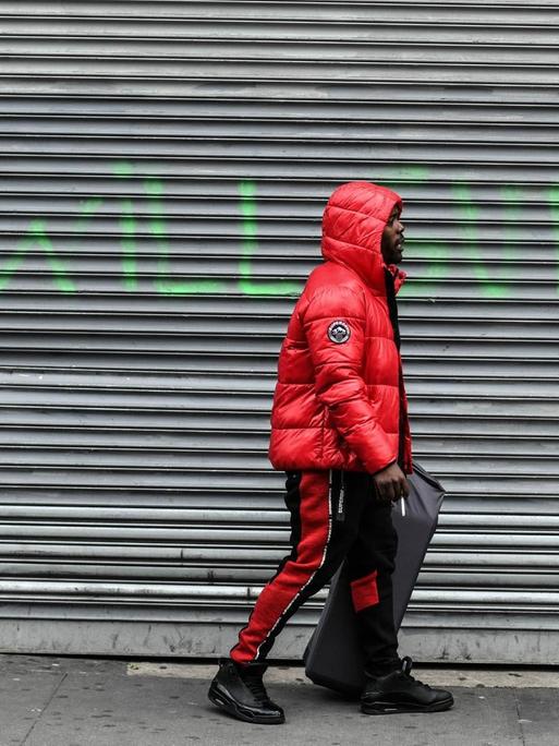 Ein Mann in der New Yorker Bronx läuft an einem geschlossenen Geschäft vorbei. Auf den Rolläden steht "We will survive", aufgenommen am 16. April 2020.