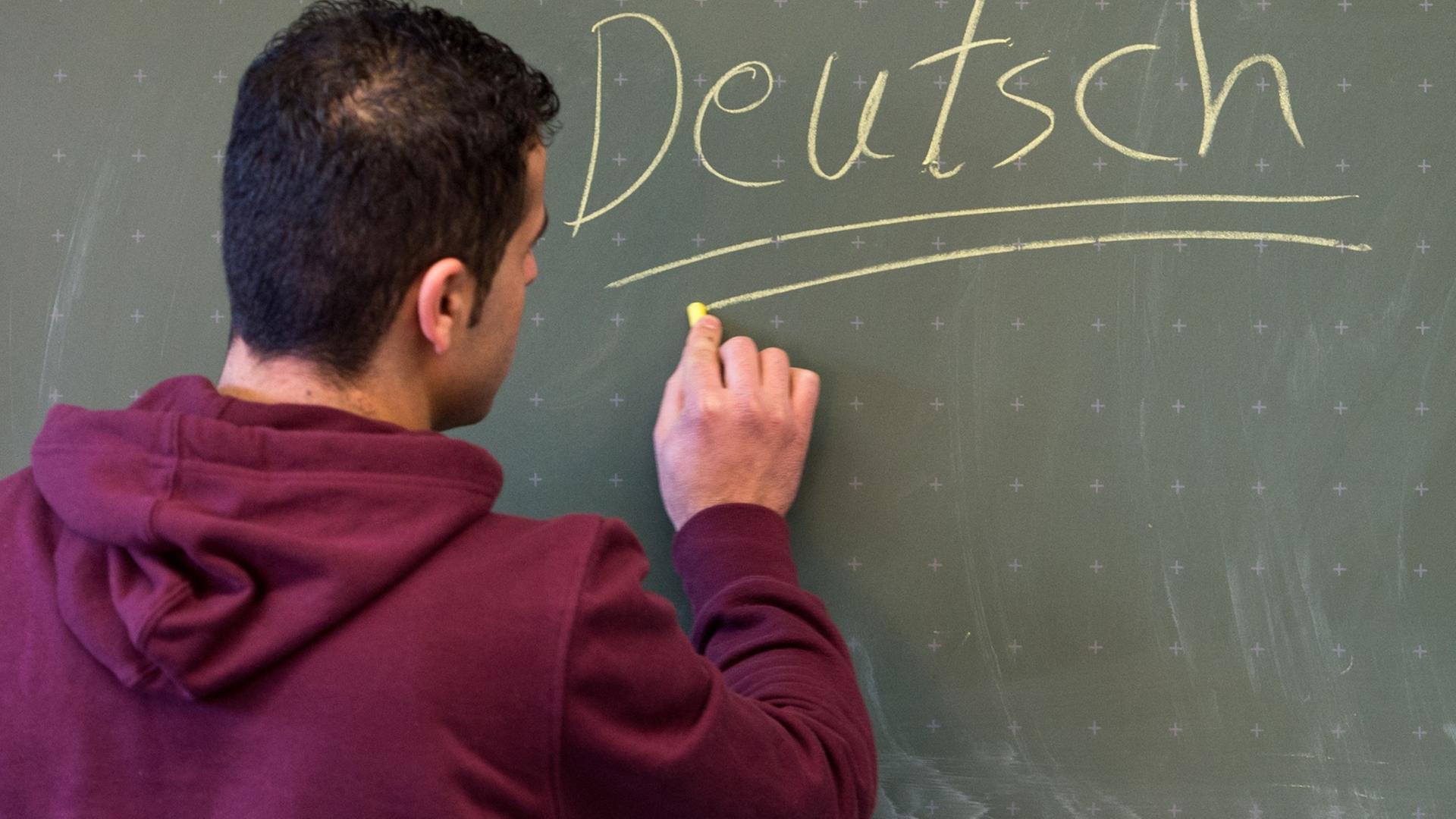 Ein Asylbewerber schreibt in einer Städtischen Berufsschule in Regensburg (Bayern) das Wort "Deutsch" an die Tafel.
