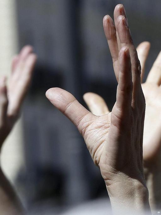 Demonstranten der spanischen 15-M-Bewegung ("Bewegung 15. Mai") heben ihre Hände in die Luft.